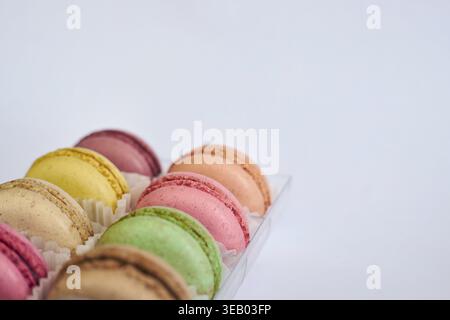 Delicate colorful cakes, French Macarons with white paperpan in plastic transparent packaging box on gray background. appetizing dessert, various maca Stock Photo