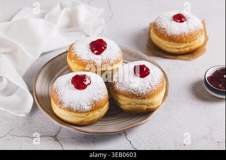 Delicious jam filled donuts with powdered sugar on a plate on the table Stock Photo