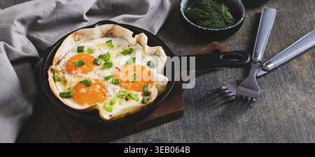 Homemade scrambled eggs in pita bread with herbs in a frying pan on the table web banner Stock Photo