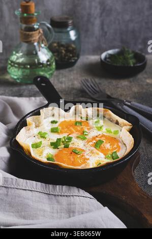 Homemade scrambled eggs in pita bread with herbs in a frying pan on the table vertical view Stock Photo