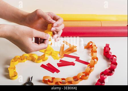 A girl's hands fold a strip of paper to make a paper chain Stock Photo