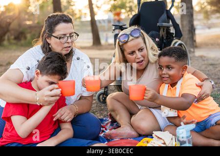 Diverse family enjoying picnic with cerebral palsy child Stock Photo