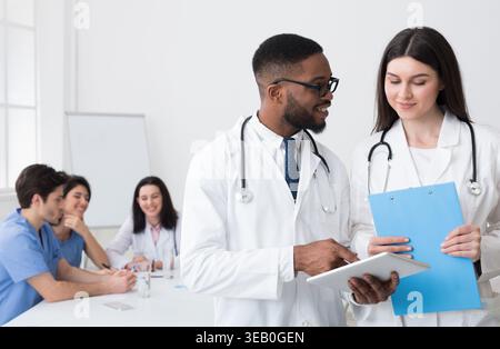Discussing Diagnosis. Diverse Doctors Using Digital Tablet Stock Photo
