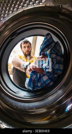Man putting laundry into washing machine drum Stock Photo