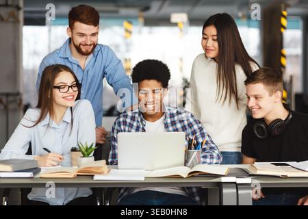 Group of Students Collaborating on a Laptop in a Modern Study Space Stock Photo