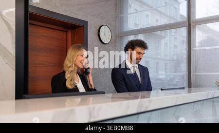 Two Corporate Reception Staff Working Together at Modern Office Front Desk Reception Stock Photo