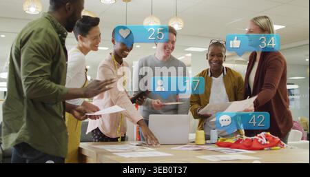Discussing team reviewing mockups on wood table in office, with red fabric, laptop, social overlay Stock Photo