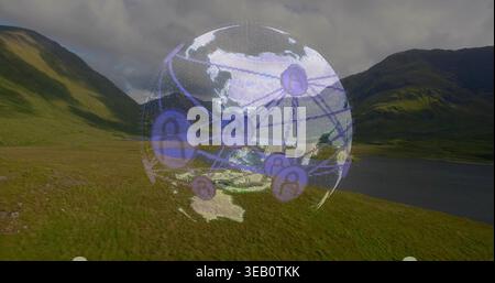 Hovering purple digital globe showing nodes over grassy valley, lake at right, cloudy mountains Stock Photo