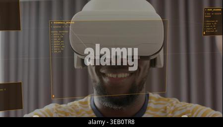 Smiling man wearing white VR headset yellow striped tee interacting with orange HUD in studio Stock Photo
