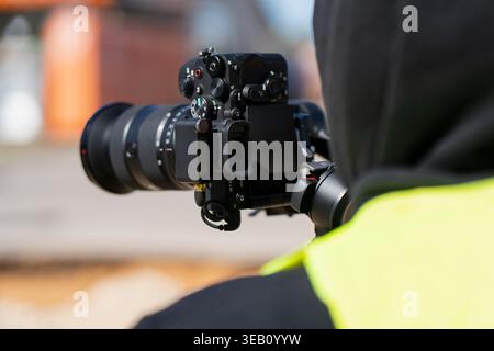 Professional filmmaker using mirrorless camera with wireless transmitter on handheld gimbal to record construction site progress for industrial docume Stock Photo