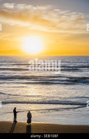 Morocco, Agadir beach, sunset on the sea, with the sun on the horizon and the sky in a yellowish tone. There are some waves in the water. The image is Stock Photo