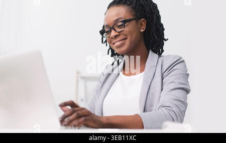 Professional Woman Working on Laptop in Modern Office Setting Stock Photo