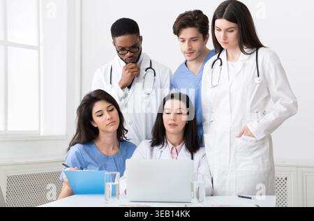 Multiracial doctors looking at laptop, working together in clinic Stock Photo
