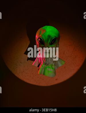 Conceptual portrait of an alien bust under dramatic green and red lighting. Symbol of extraterrestrial life, artificial intelligence, and the unknown. Stock Photo