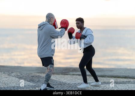 Woman practicing boxing punches with coach outdoors Stock Photo