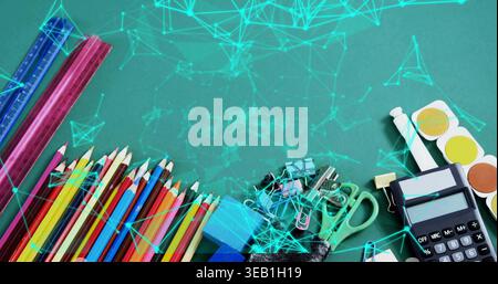 Displaying school supplies spreading along green chalkboard, with colored pencils rulers calculator Stock Photo