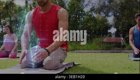 Kneeling man in red sleeveless top meditating on gray mat in park, showing bracelet and grid Stock Photo