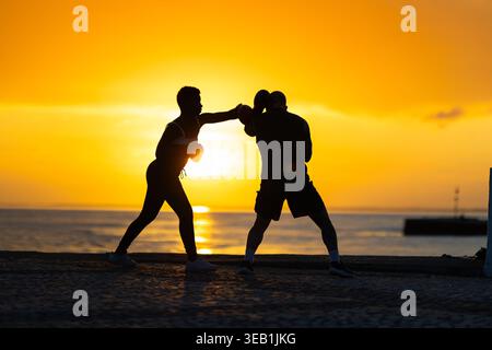 Athletes training boxing at golden hour sunset seascape Stock Photo