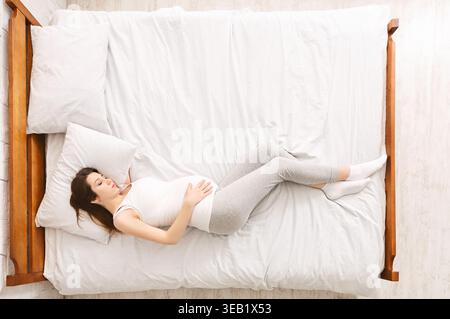 Woman Resting Comfortably on a Serene Bed in a Cozy Bedroom During the Morning Hours Stock Photo