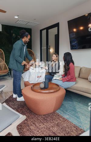 Startup Team Sharing Pizza Living Room, Casual Colleagues Gathered On Sofa Around Low Table, Laughter And Conversation, Warm Lighting, Modern Interior Stock Photo