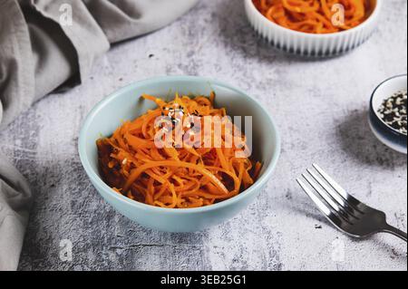 Spicy Korean carrots with sesame seeds in a bowl on the table Stock Photo