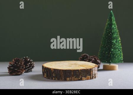 Podium made from a cut tree trunk, Christmas tree and pine cones on a green background Stock Photo