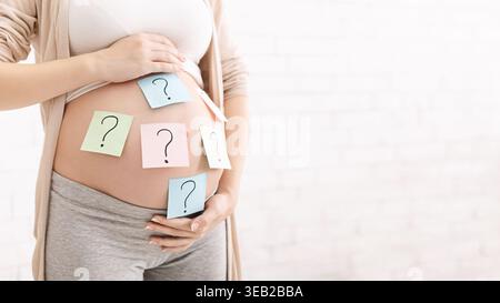Expecting a Baby With Question Marks on Colorful Sticky Notes on Pregnant Belly Stock Photo