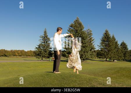 Beautiful newlyweds dancing joyfully barefoot on the green grass on a sunny day. A cheerful couple in love, a happy moment, a bride and groom. Ukraini Stock Photo