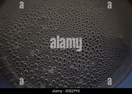 Close up of boiling water with small bubbles forming in a heated pan surface Stock Photo