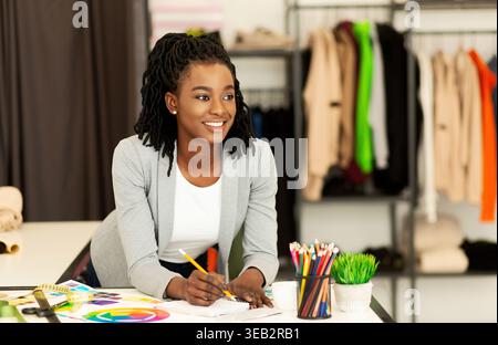 Young Designer Conducts Creative Work in Stylish Studio Filled With Clothing Stock Photo