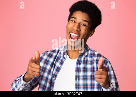 Excited guy pointing fingers at camera over pink background Stock Photo