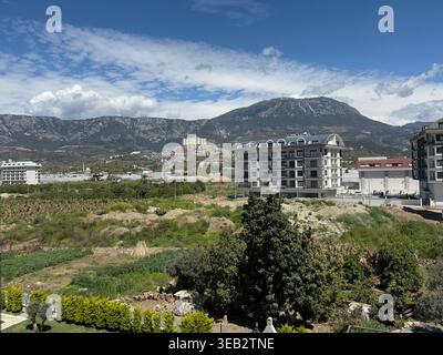 Mountain view from urban area with cloudy sky and residential buildings. Mobile photo Stock Photo