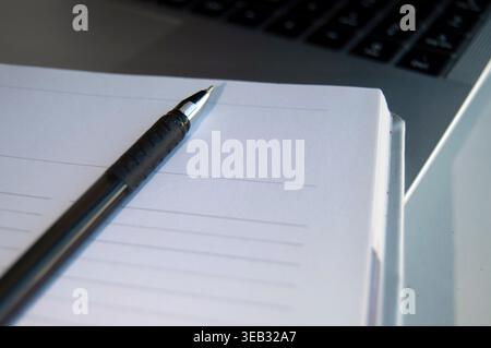 A pen and a notebook next to a laptop. Stock Photo
