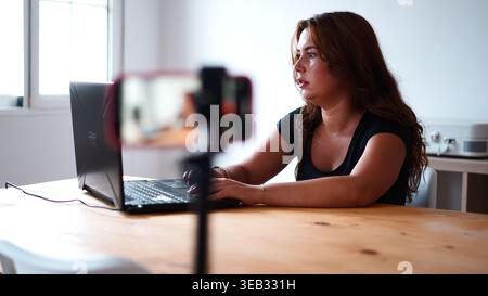 Young woman creating content for social media, streaming live from home studio Stock Photo