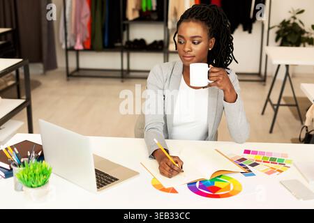 Creative Designer Working at a Modern Studio While Enjoying a Cup of Coffee Stock Photo