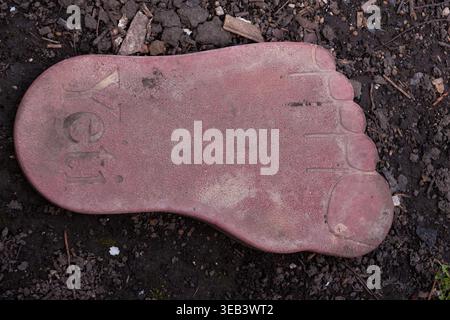A close-up of a decorative paving tile shaped like a human foot with the inscription Yeti. The image highlights a unique urban design element used in Stock Photo
