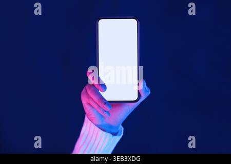 Hand Holding Blank Smartphone Under Vibrant Blue and Purple Lighting Stock Photo