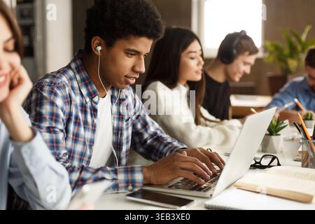 Student learning lessons in school library, using laptop Stock Photo