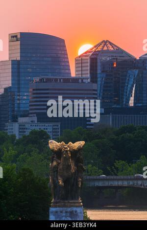 View of the Rosslyn skyline at sunset with modern skyscrapers and the Sacrifice statue in the foreground over the Potomac River in Arlington, Virginia Stock Photo