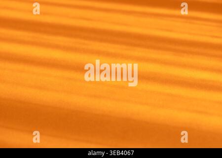Abstract orange background showing sunbeams casting diagonal shadows and light stripes Stock Photo