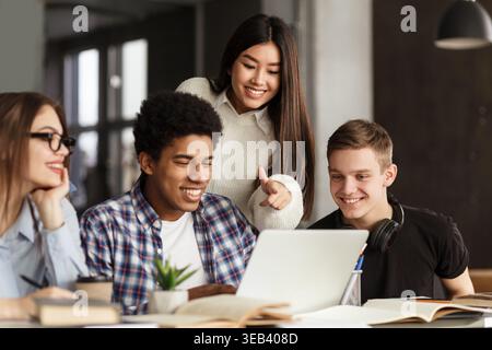 College students using laptop in library, studying together Stock Photo