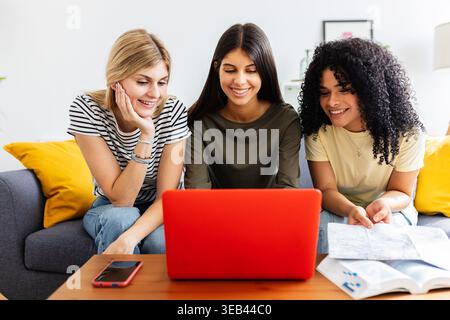 Group of young women planning travel together using laptop at home Stock Photo