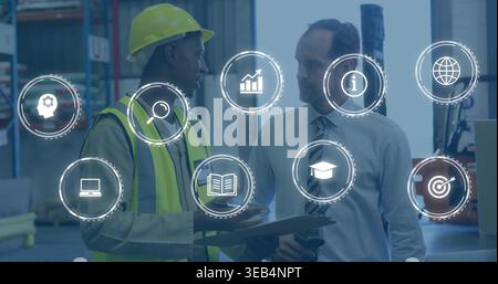 Checking worker in yellow hard hat and hi-vis vest, manager holding tablet in warehouse, clipboard Stock Photo