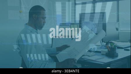 Studying African American man in light shirt reviewing plans at office with monitors, copy space Stock Photo
