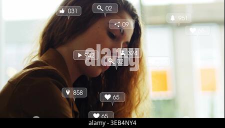 Contemplating woman in brown jacket facing right at cafe window, with social notification overlays Stock Photo