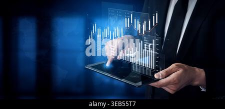 A professional man in a suit interacts with a tablet displaying holographic financial graphs and charts, representing modern business analytics and Stock Photo
