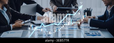 A diverse business team collaborates in a modern office, analyzing financial data, strategies, and growth during a meeting focused on success and Stock Photo