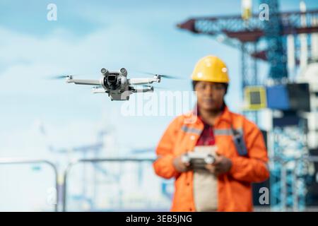 Drilling rig specialist using drone for quick overview and evaluation of hard to reach areas. Offshore platform worker uses remote control UAV for preventive maintenance planning Stock Photo