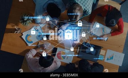 A diverse group of professionals collaborates at a table, surrounded by charts and digital security graphics, symbolizing modern teamwork and data Stock Photo