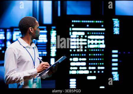 Experienced admin analyzing server systems performing data backups and providing centralized storage. Technician adjusting Uninterruptible Power Supply ensuring proper operating Stock Photo